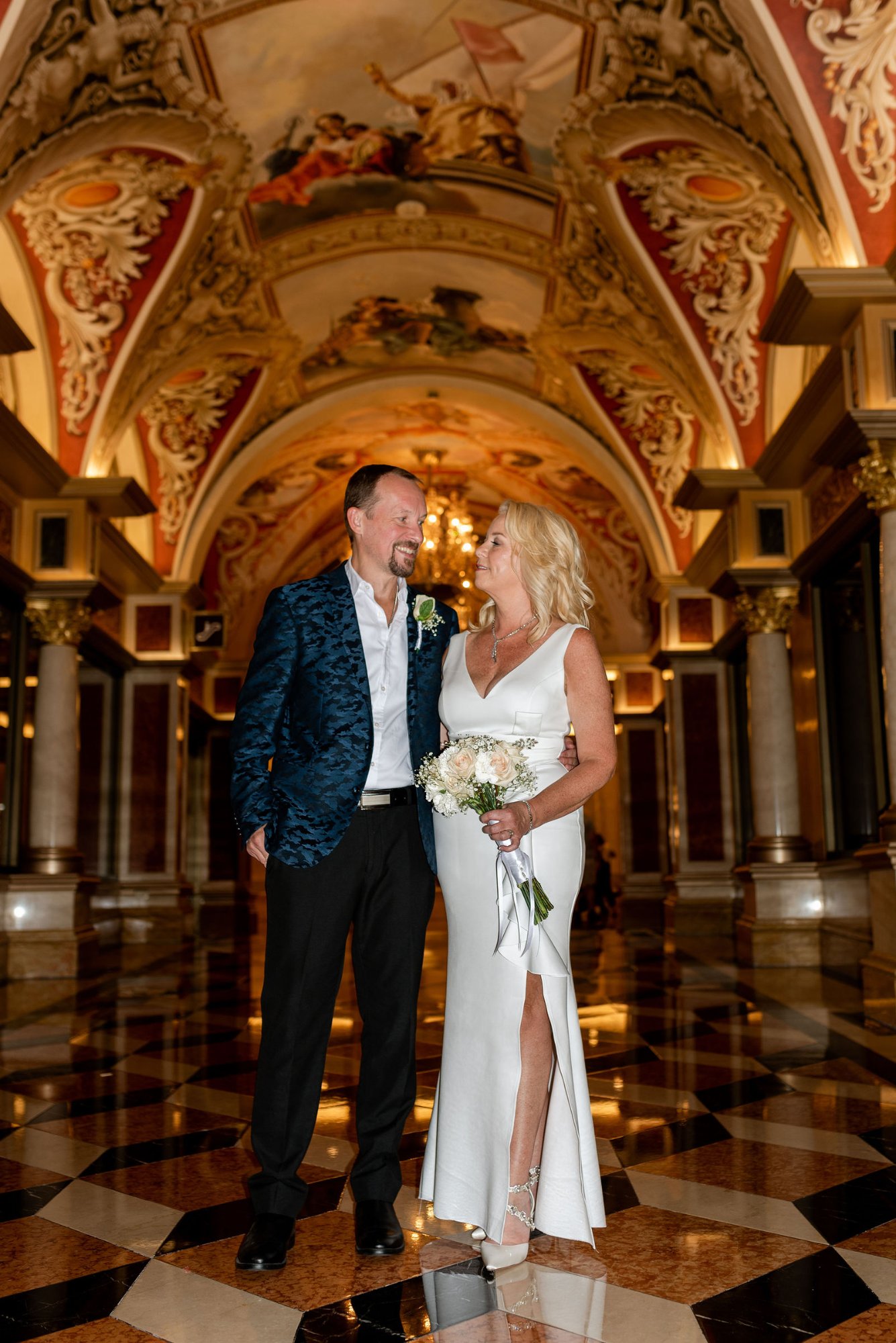 Newlyweds in ornate Venetian hotel corridor